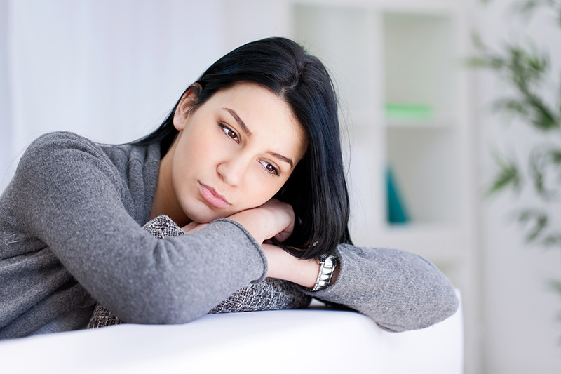 Woman resting head on crossed arms with a concerned look.